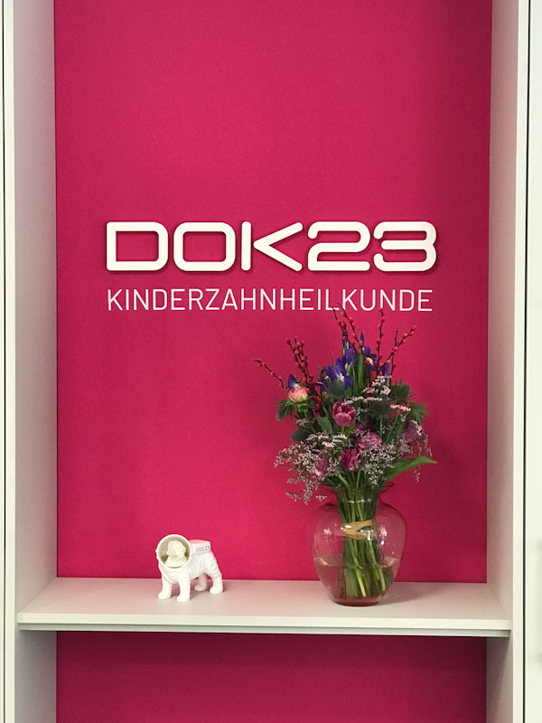 3D-Acrylbuchstaben und Folienschrift an pinkfarbener Wand, Kinderzahnheilkunde DOK 23